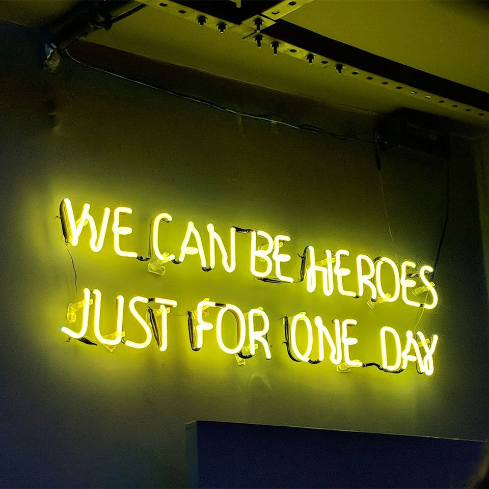 A neon sign saying "We can be heroes just for one day", a quote by musician David Bowie